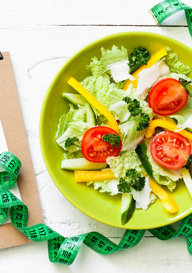 Healthy eating and Diet concept. Green Plate with fresh vegetables salad and measurement on wooden table.